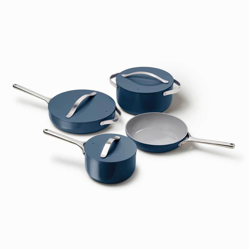 Angled overhead of navy 4-piece ceramic cookware set showing light-gray nonstick interior on white background