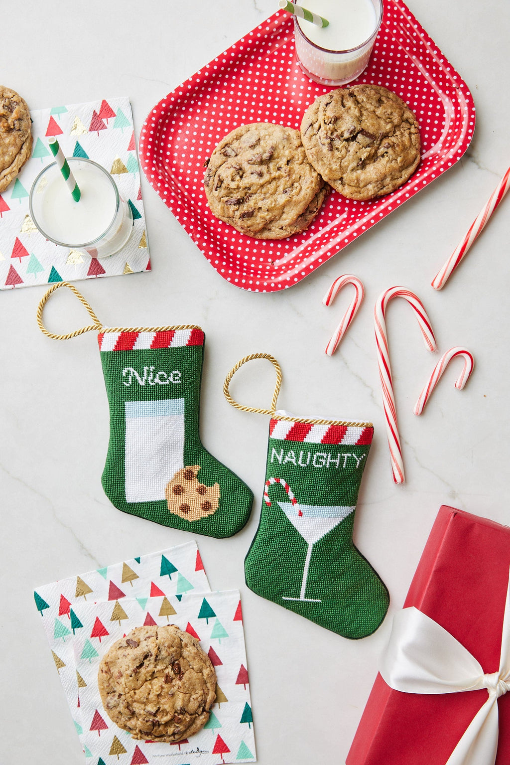 Holiday-themed display with Nice and Naughty Bauble Stockings, cookies, milk, and candy canes on festive backdrop
