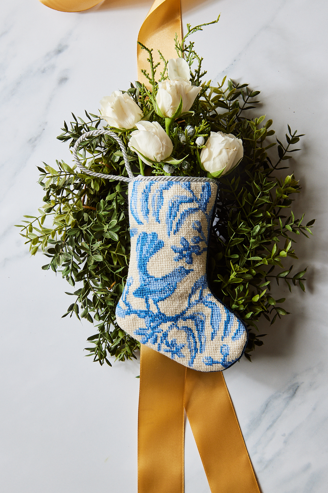 Top view of Sarah’s Songbird Bauble Stocking showcasing blue bird needlepoint with holiday greenery and gold ribbon