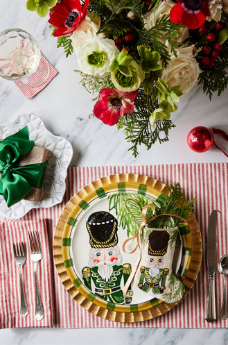 Holiday-themed table styled with Bauble Stockings, nutcracker plate, festive greenery, and red decor accents