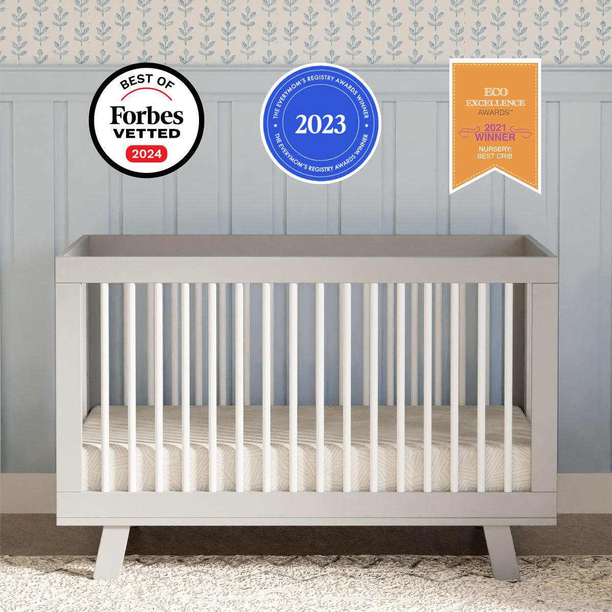 Front view of Hudson three in one convertible crib in grey and white with rounded spindles flared feet and award badges