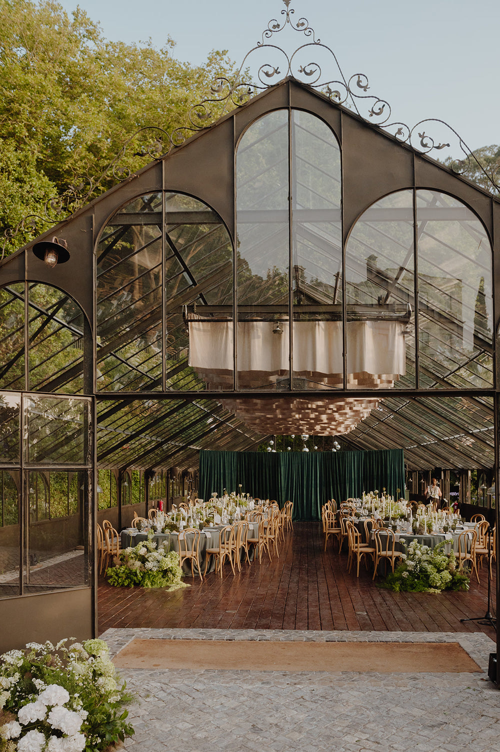 Wedding reception tables arranged inside a glass greenhouse in Sintra, Portugal