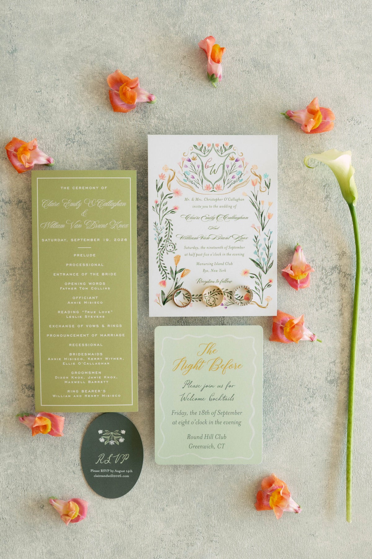 Top-down view of wedding stationery showcasing floral designs, ceremony details, wedding rings, and coral flowers on textured fabric