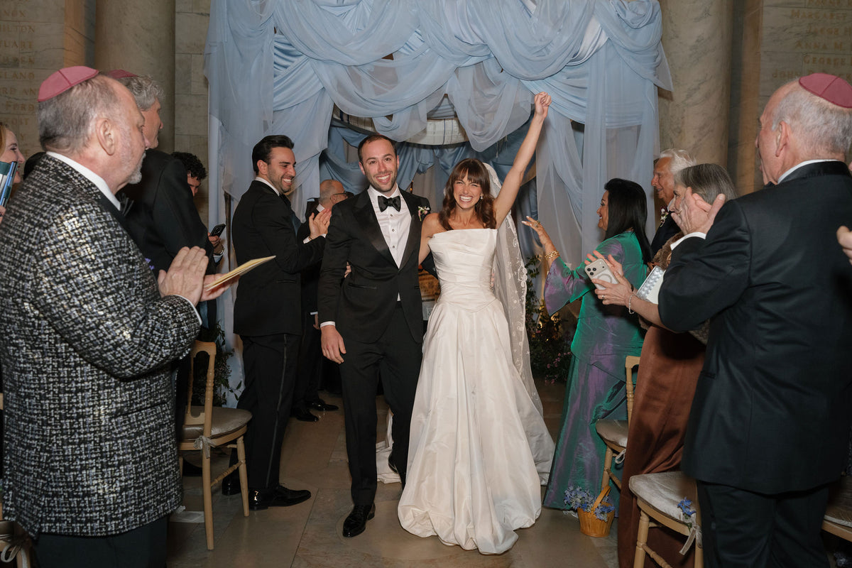 Bride and groom celebrate with guests beneath draped fabric at their New York Public Library wedding