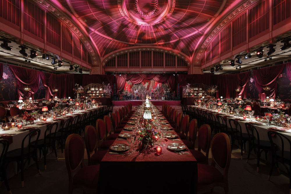 Wedding reception with candlelit tables beneath a domed ceiling and red drapery