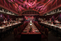 Wedding reception with candlelit tables beneath a domed ceiling and red drapery