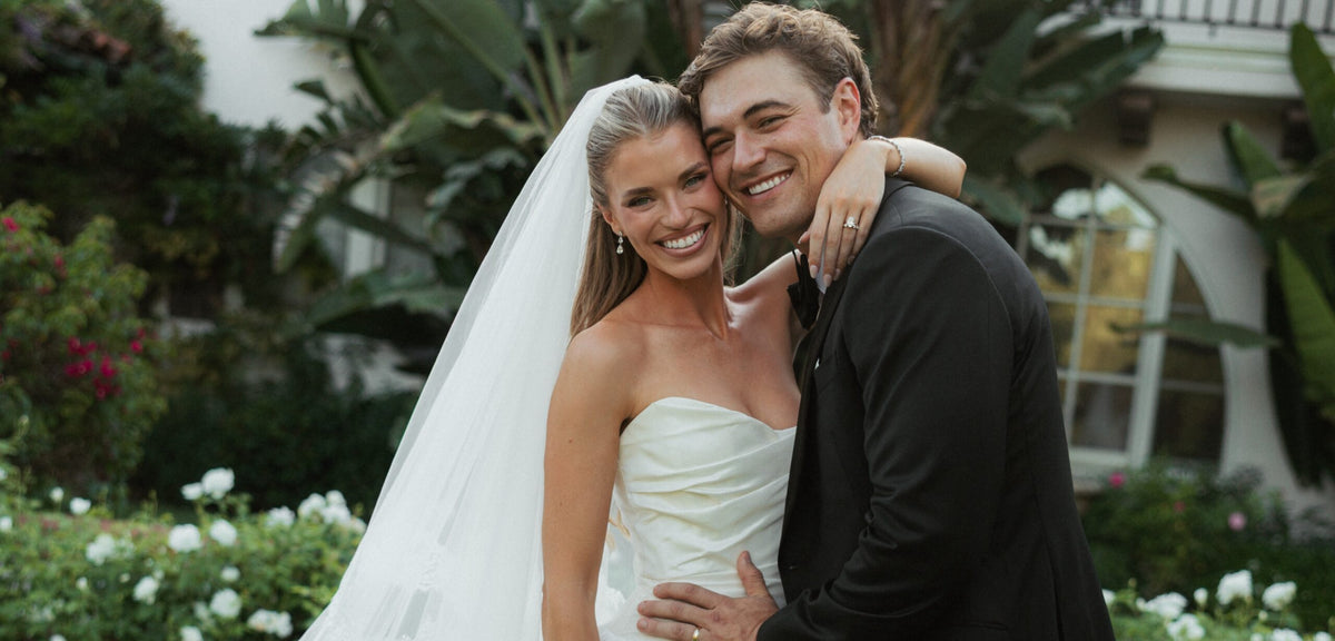 Lou Martines and Mac Kaufman embrace in a garden at their California summer wedding