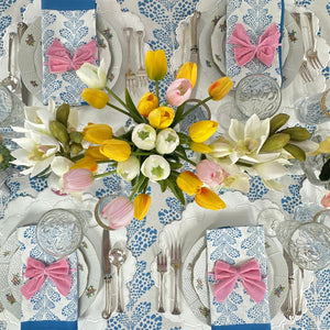 Easter-themed table setting with flowers, bow-knotted napkins, and decorative plates.