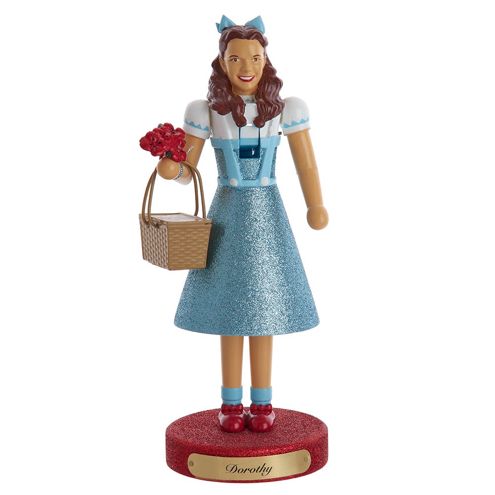 Front of Dorothy Wizard of Oz nutcracker showcasing blue glitter dress, ruby slippers and flower basket on red glitter base