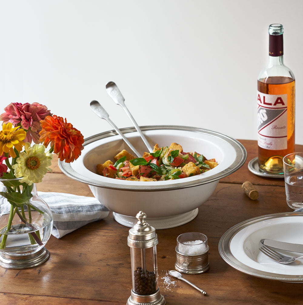 Three-quarter view of Luisa Round Footed Serving Bowl, Large showcasing rope bordered Italian pewter rim and ceramic base on a dining table