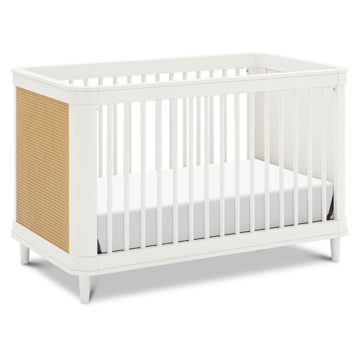 Three-quarter view of Marin with Cane 3-in-1 convertible crib in warm white and honey cane, showcasing curved rails and cane panel