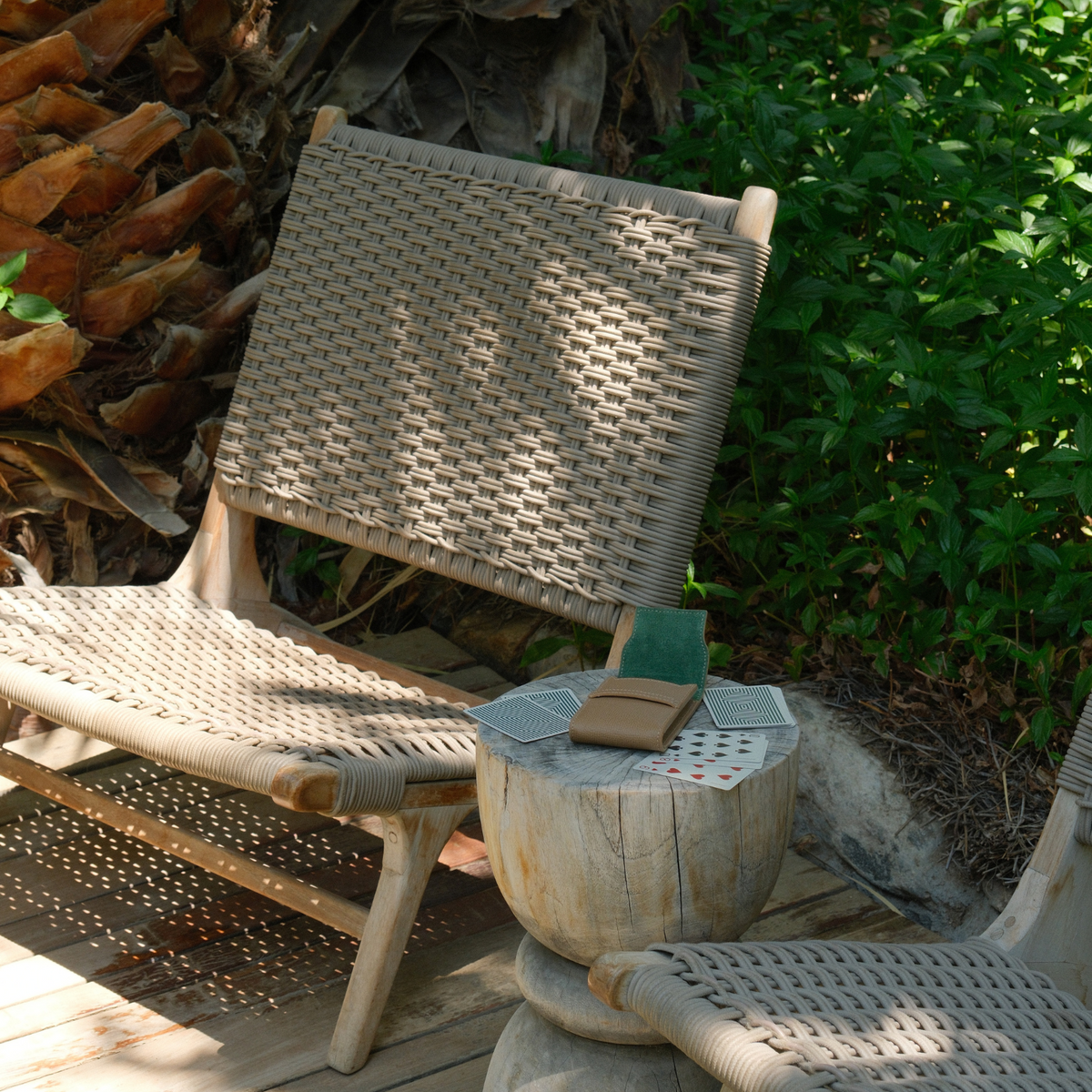 Angled view of Palmilla leather card set showing tan case with green suede and cards on a wooden stool by woven chairs