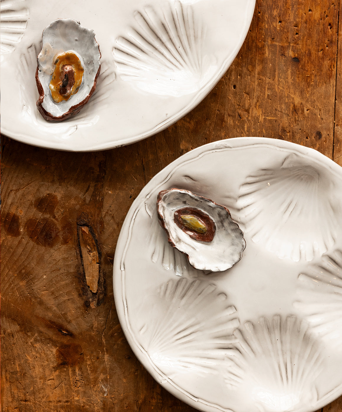 Top-down view of Radi Simple oyster platter showcasing shell-shaped wells and smooth white glazed stoneware on a wooden table
