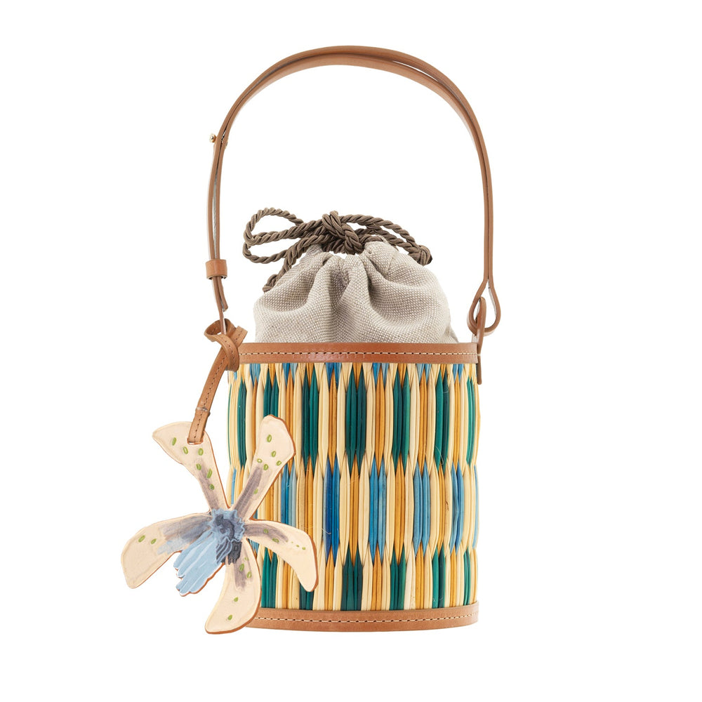 Front view of Cupid Madras bucket bag with blue and green woven madras, leather strap, drawstring pouch, and orchid charm