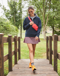 Model is wearing the Ribbed Varsity Quarter Zip in Navy over the Classic Short Sleeve in Super White/ Navy Stripe with the Flounce Skort in Navy/ Cherry Stars