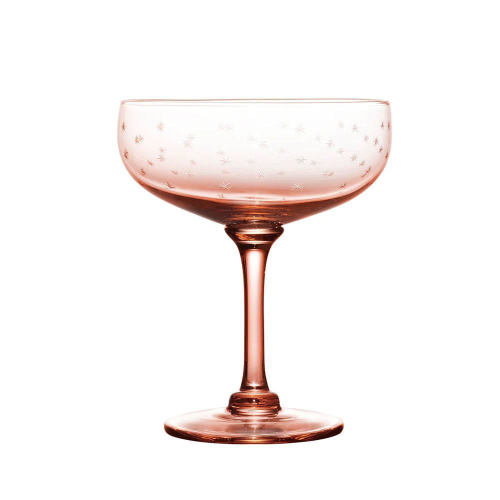 Front view of rose-colored coupe cocktail glass showcasing engraved star pattern on the bowl with white background