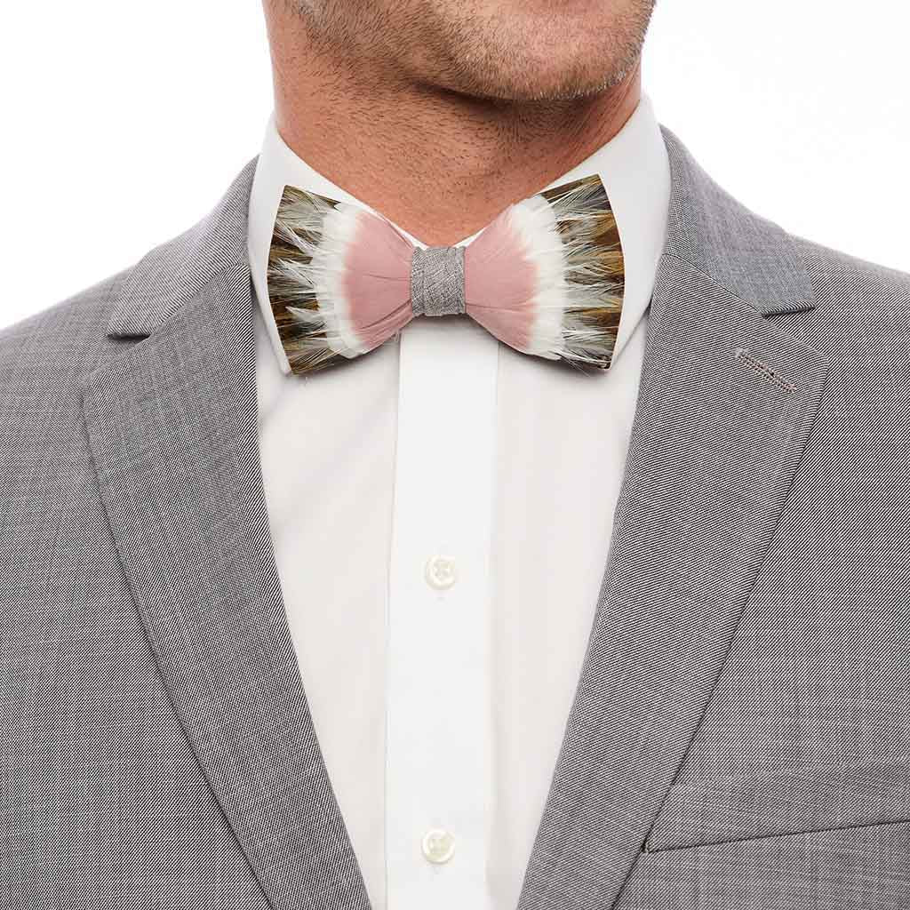 Front view of Royal pheasant feather bow tie showcasing pink center and brown-and-white feather tips on model in light gray suit