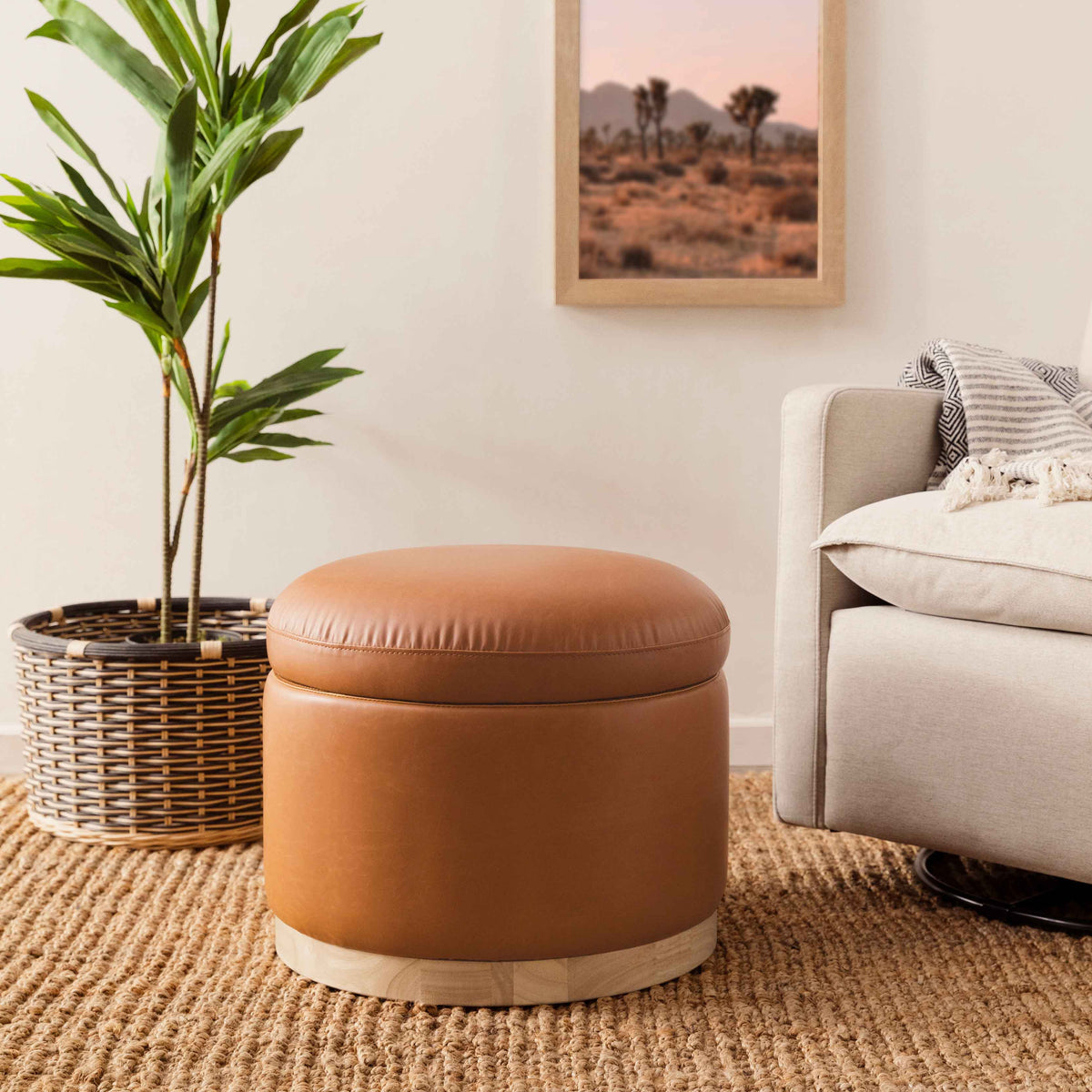 Front view of Naka Storage Ottoman showcasing vegan tan leather upholstery and light wood base in a living room