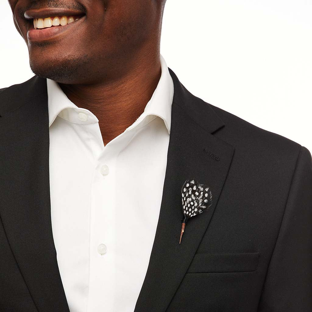 Close-up of Seattle feather lapel pin showcasing a black-and-white spotted feather on a black suit lapel