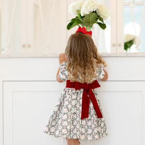 Back view of Short Sleeve Grace Dress in Regent Wreaths with red velvet sash and full gathered skirt against a white vanity