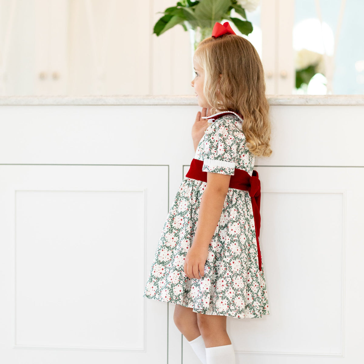 Side view of Short Sleeve Grace Dress in Regent Wreaths with red velvet Peter Pan collar, sash, puff sleeves, and full skirt