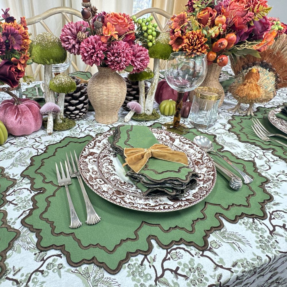 Decorative table setting with flowers, pumpkins, and a green placemat.