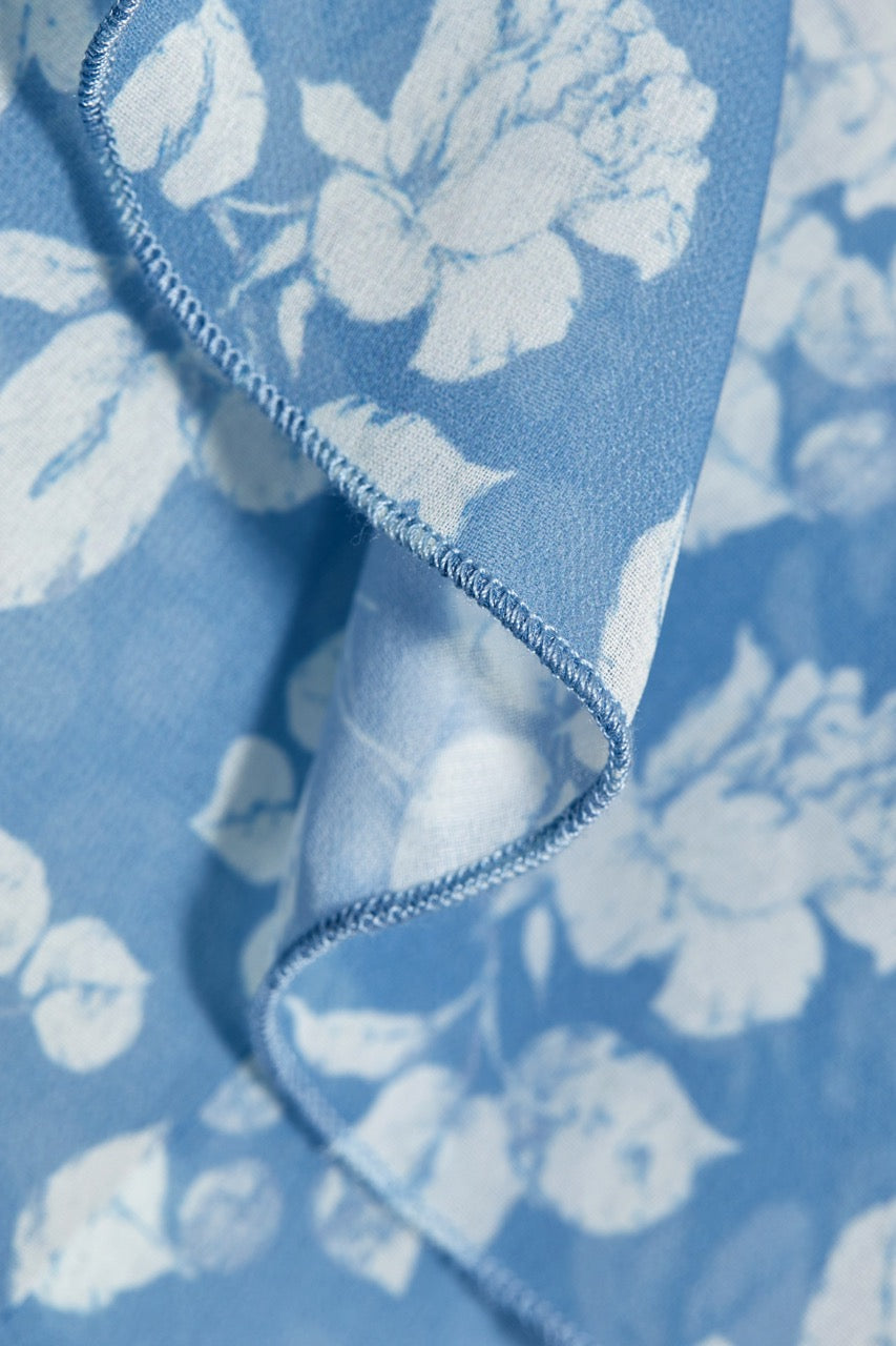 Close-up of Shellona Dress in Blue Floral showcasing blue floral cotton fabric and a stitched edge