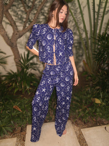 Model wearing a blue printed pajama set with matching top and pants, standing outdoors