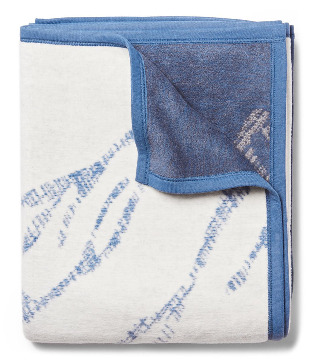 Blue and white blanket with ski track pattern and blue binding edges.