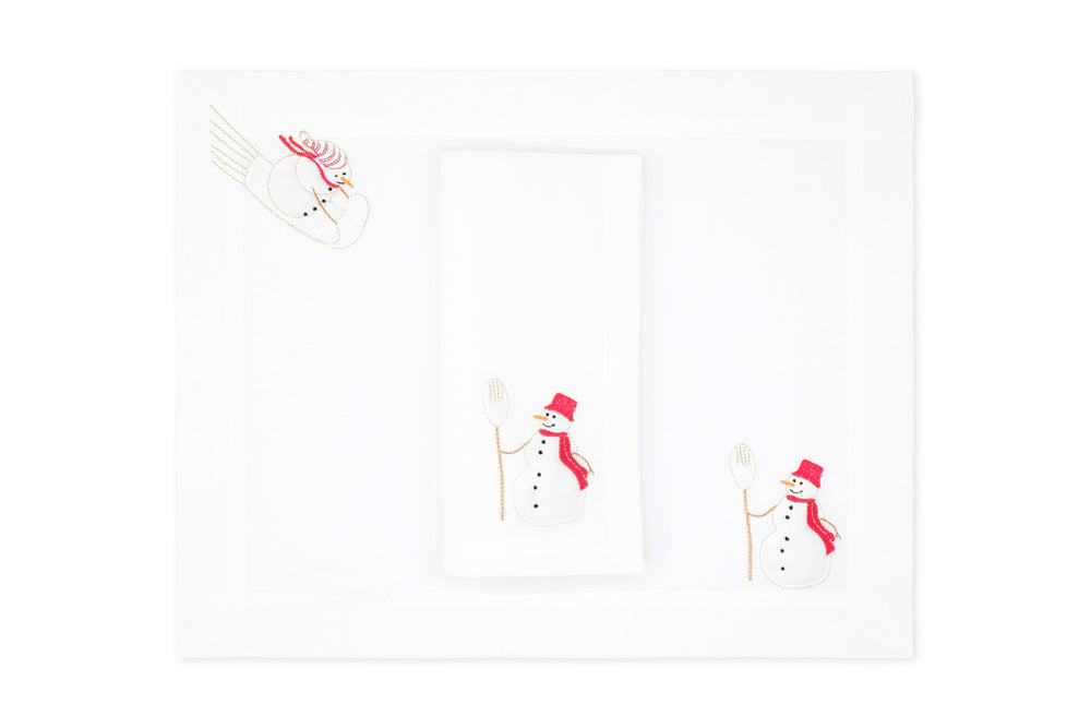 Top view of linen placemat and napkin set showcasing embroidered snowman motif on white Italian linen with white background