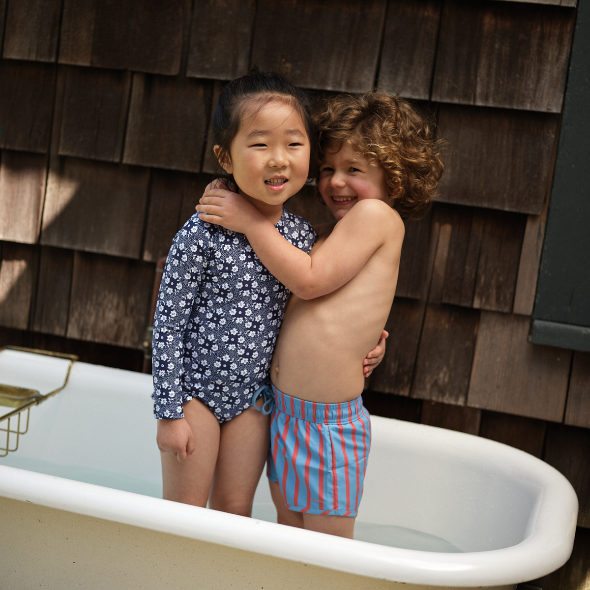 Front view of Boys Maritime Stripe Boardie showcasing blue and red stripes with drawstring waistband on child in a tub