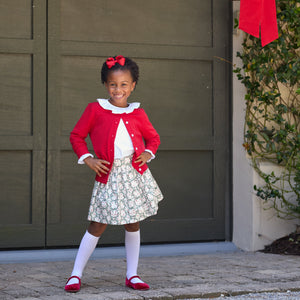 Girls’ Sutton Skirt in Regent Wreaths, featuring a festive green wreath and red star print on white with a full gathered silhouette.