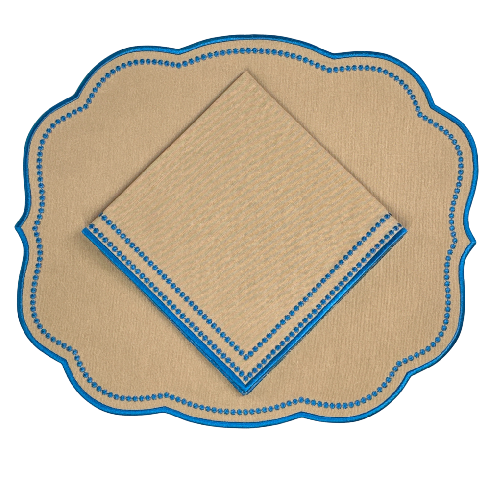 luxury tan napkin with blue trim embroidery on a matching placemat