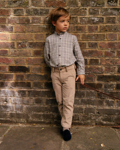 Young boy in formal attire standing against a brick wall