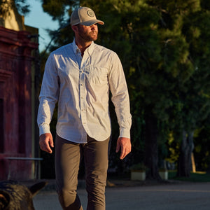 A man in the Tom Beckbe Powell Performance Shirt enjoys a tree-lined street, protected by UPF 30+ coverage.