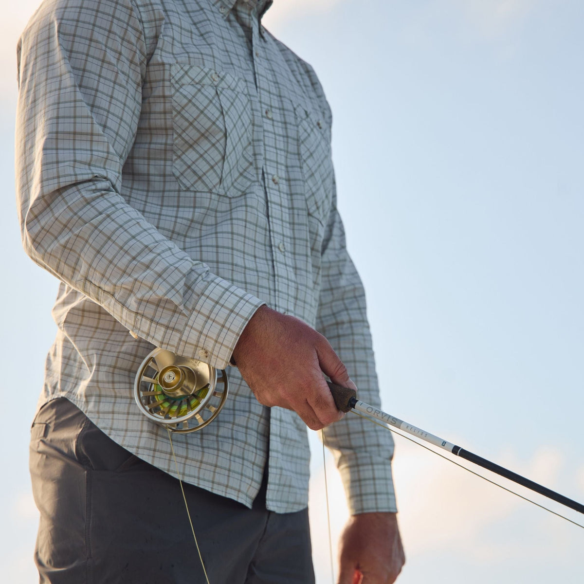 Someone in a Tom Beckbe Tidewater Shirt holds a rod, enjoying the clear sky.