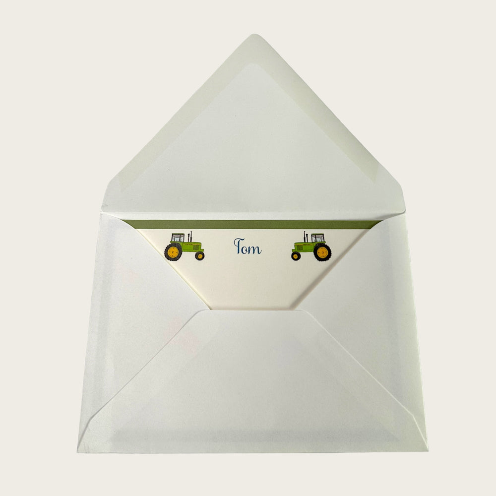 Top view of opened tractor notecard envelope showing personalized liner with two green tractor illustrations and the name Tom