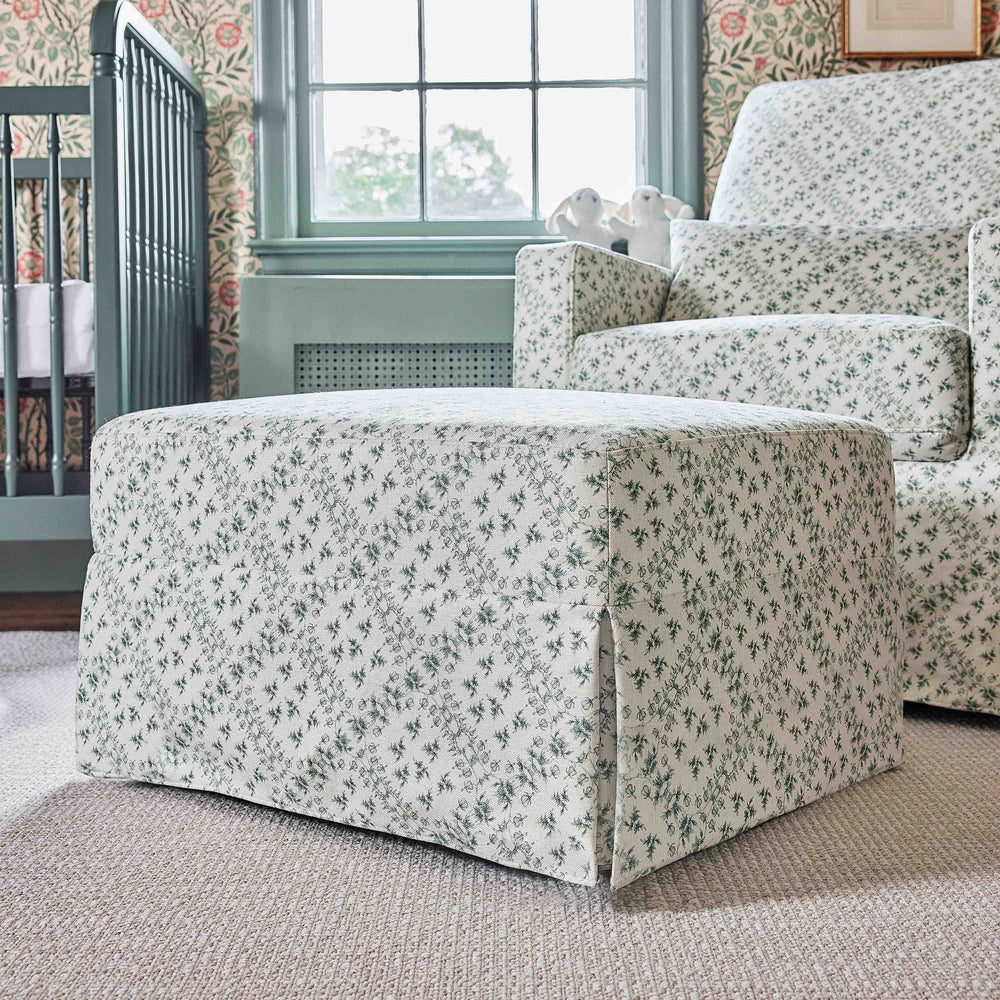 Three quarter view of Crawford gliding ottoman showcasing green lattice performance eco weave fabric and skirted base in a nursery
