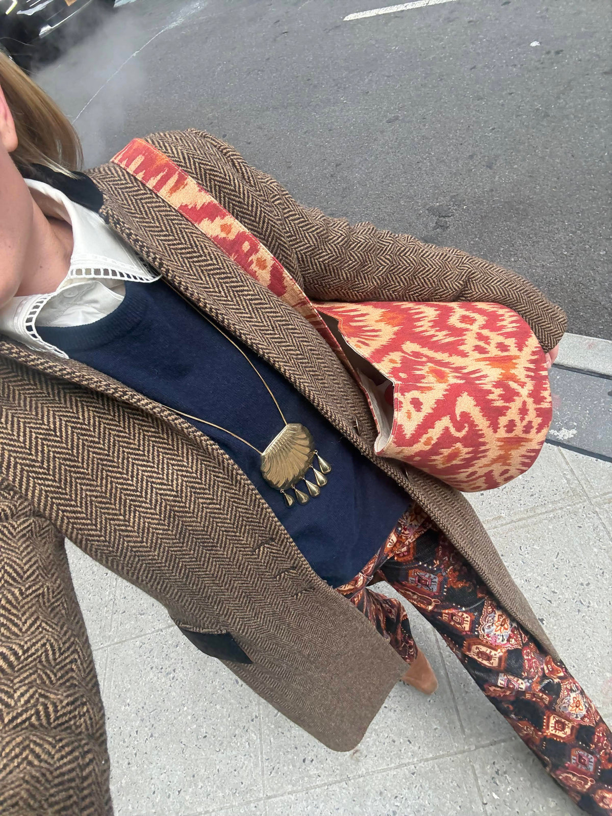 Annabelle tote bag in red ikat worn on shoulder by a person walking on a city sidewalk