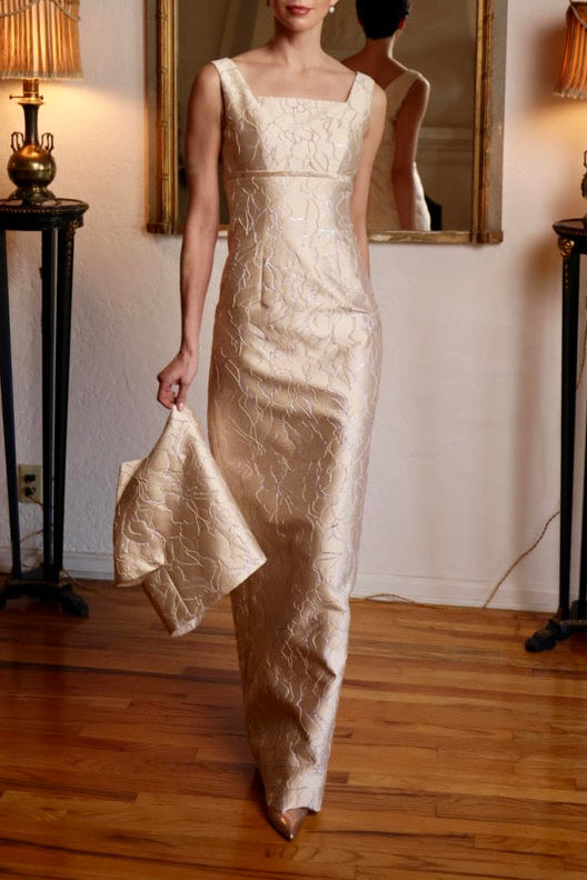 Front view of high-waisted gold and silver lamé gown with square neckline, fitted floor-length silhouette and matching clutch