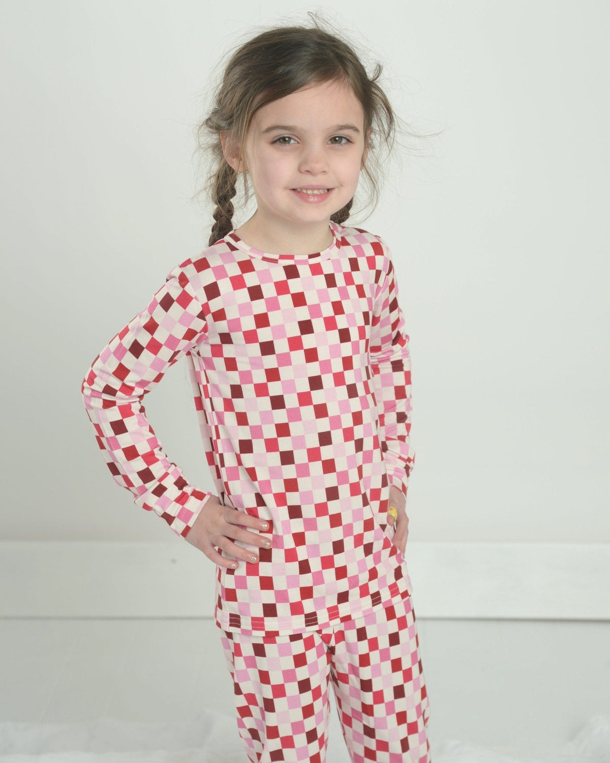 Front view of pink checkered bamboo two-piece pajamas on child model, long-sleeve top and matching pants