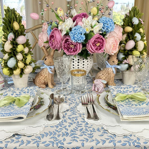 Easter-themed table setting with floral centerpieces, bunny decorations, and colorful eggs.