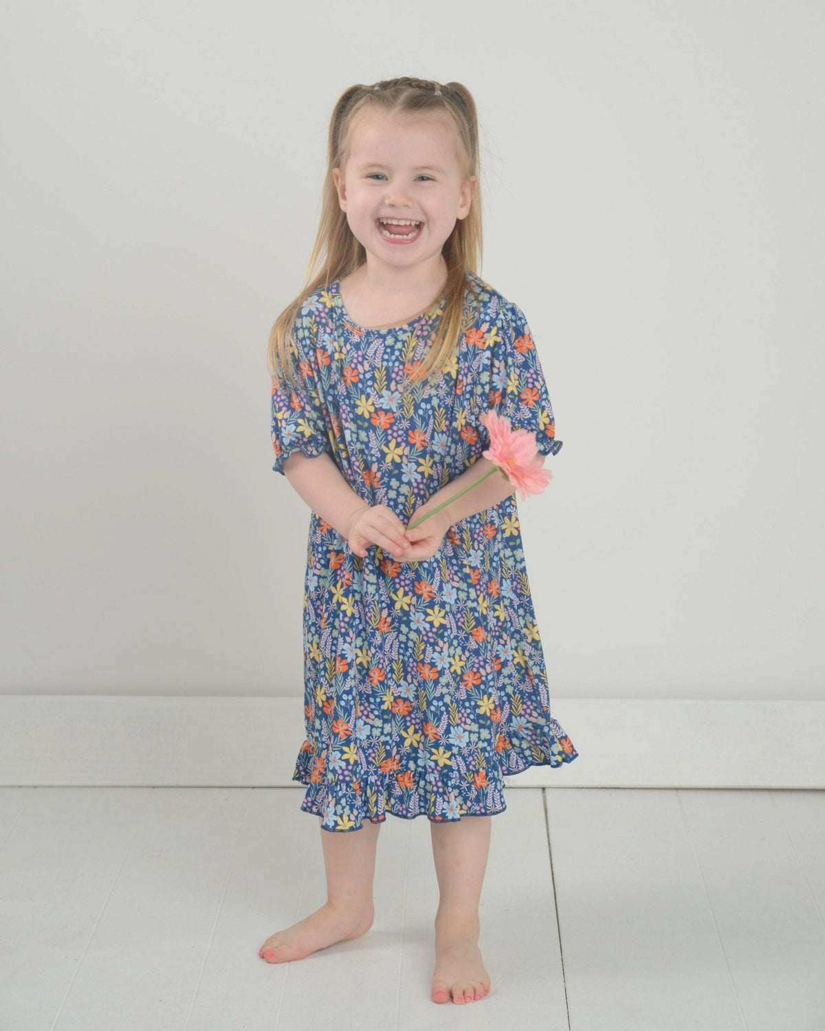 Front view of floral bamboo nightgown on a smiling girl model, short sleeves and ruffle hem against a plain light background