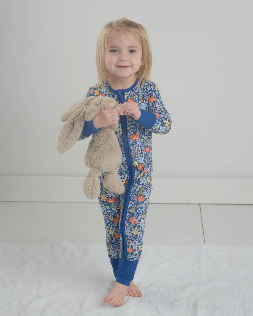 Front view of Wildflower Bamboo romper showcasing blue floral print and two way zipper against light background