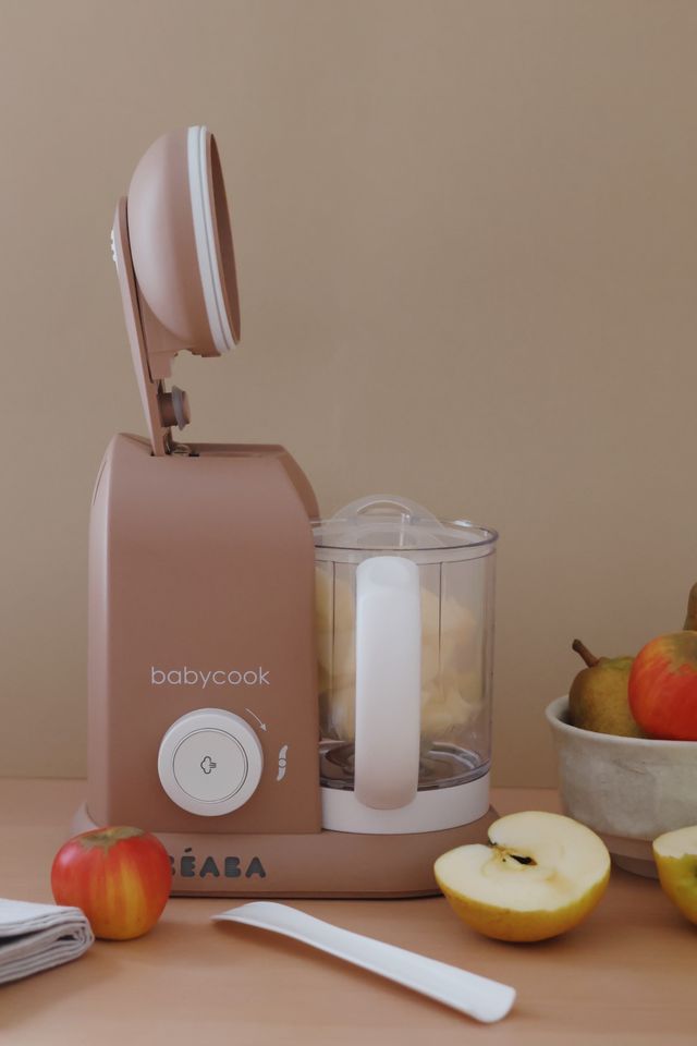 Front view of Babycook Solo in Praline showcasing its clear blending bowl with apples and cut fruit on a countertop