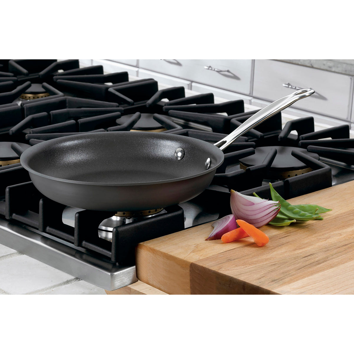 Angled view of Chef’s Classic® 8-inch skillet with black hard anodized body and stainless steel handle on gas stovetop
