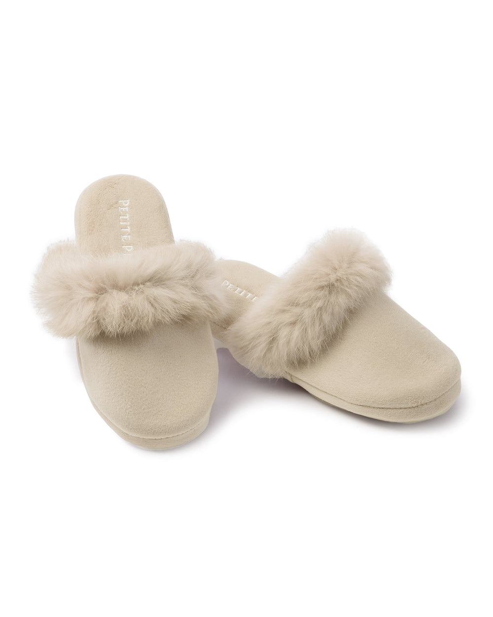 Three-quarter view of pair of beige velvet mule slippers with plush faux fur trim on white background