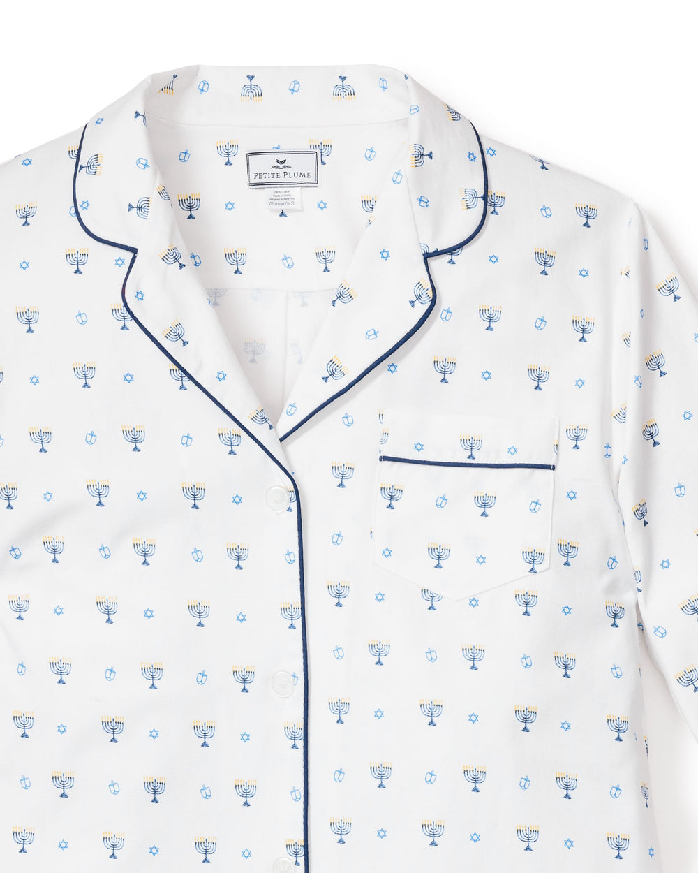 Front close-up of Hanukkah pajama top with navy piping, chest pocket, and menorah, dreidel, and star print on white