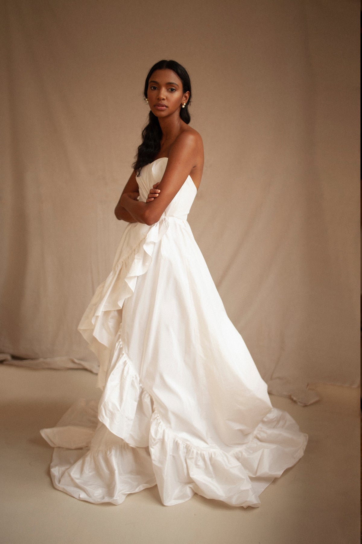 Three-quarter view of the Crisp Dress showcasing its white heart-shaped strapless top and billowing silhouette with a beige background