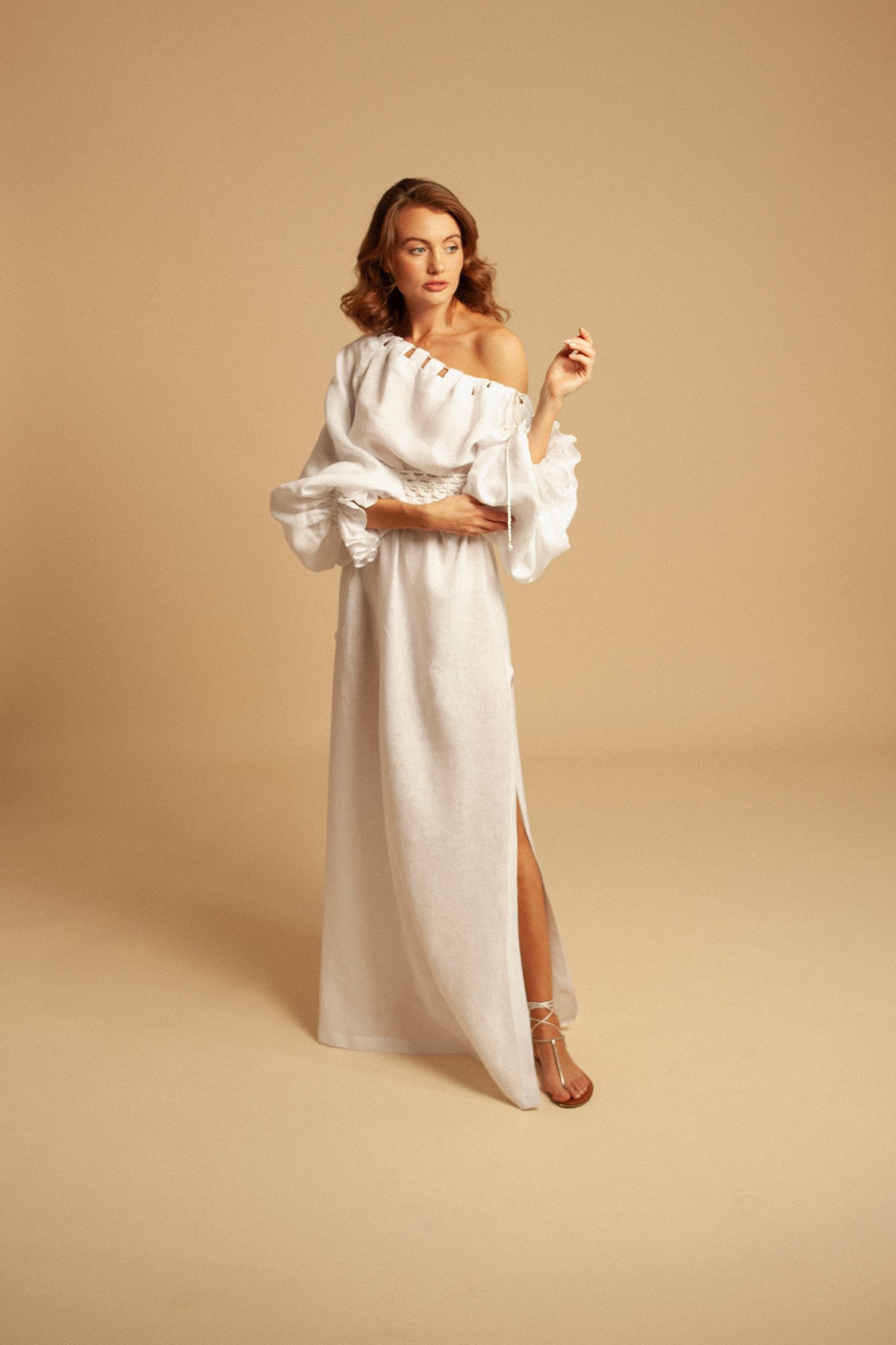 Front view of Jazmin Dress showcasing white linen, off-the-shoulder top, bubble leaves, and side slit on beige